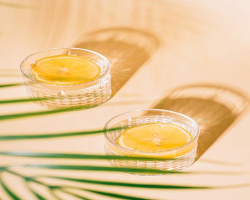 Crystal clear glass of water with fresh lemon slices on a bright table